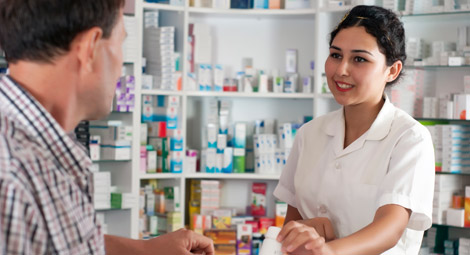 A pharmacist stood behind his counter with his arms folded
